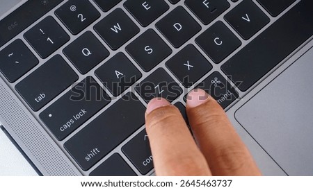 Full frame of finger pressing command and Z letter button or cmd + Z on a laptop keyboard, shortcut keys for undo isolated on black background