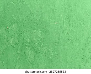 Full frame horizontal abstract of bright green painted concrete wall texture with rough bumpy cement surface