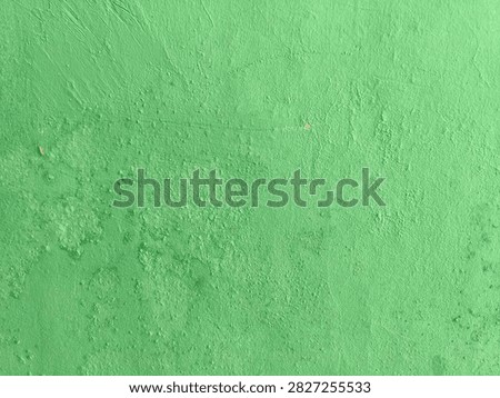 Full frame horizontal abstract of bright green painted concrete wall texture with rough bumpy cement surface