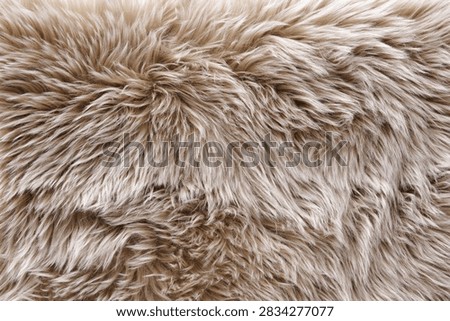 Full frame macro background of soft beige fluffy faux fur rug pile. Ideal texture for cozy winter decor, warm fashion textiles, and luxury lifestyle backgrounds.