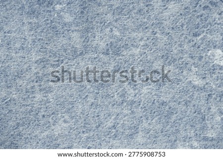 Full frame macro shot of light blue acid-wash denim material. Detailed textile texture background for fashion, apparel, and clothing design projects.
