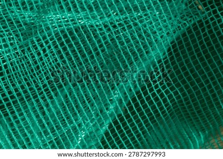 Full frame macro texture background of a vibrant green woven plastic net featuring a regular grid pattern