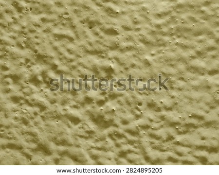 Full frame macro texture of bumpy yellow painted wall surface.