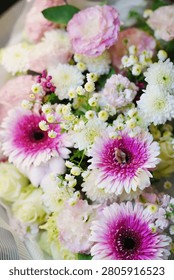 Full frame macro texture shot of a romantic holiday floral arrangement featuring bright pink gerbera blossoms, small white roses, and herbs