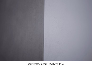 Full frame minimalist texture of two contrasting wall surfaces showing a rough dark grey concrete corner and a smooth light purple painted background