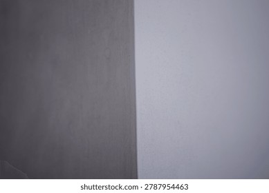 Full frame minimalist texture of two contrasting wall surfaces showing a rough dark grey concrete corner and a smooth light purple painted background