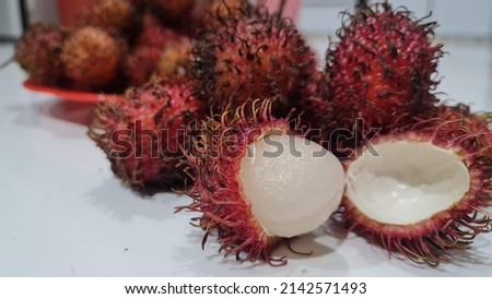 Full frame shoot of bunch of red rambutan fruits. Close-up of peeled rambutan. Top view healthy fruits rambutans. The sweet fruit is a round to oval single-seeded berry covered with fleshy pliable spi