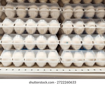 Full frame shot of multiple rows of white eggs in transparent plastic cartons for sale on a supermarket shelf for food supply concept.