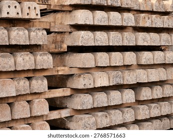 Full frame shot of stacked concrete railway sleepers separated by wooden
planks. The weathered grey concrete blocks feature industrial bolt holes and a
repetitive, geometric pattern. The image highlights the raw texture of
construction materials and the organized, heavy-duty nature of infrastructure
components in a storage or industrial setting.