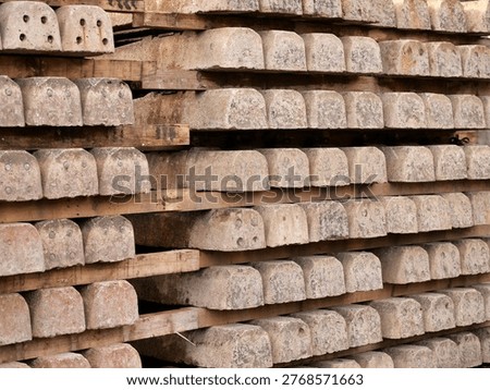 Full frame shot of stacked concrete railway sleepers separated by wooden
planks. The weathered grey concrete blocks feature industrial bolt holes and a
repetitive, geometric pattern. The image highlights the raw texture of
construction materials and the organized, heavy-duty nature of infrastructure
components in a storage or industrial setting.
