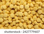 Full frame shot of yellow pills. Medicines are chemicals or compounds used to cure, halt, or prevent disease.