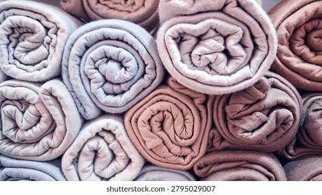 Full frame stack of neatly rolled pastel towels creating a soft and colorful texture background. Cozy fabric arrangement symbolizing cleanliness, comfort, hygiene, relaxation, and home living. Ideal for spa, wellness, bathroom, hospitality, laundry, textile, interior design, and lifestyle concepts.