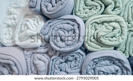 Full frame stack of neatly rolled pastel towels creating a soft and colorful texture background. Cozy fabric arrangement symbolizing cleanliness, comfort, hygiene, relaxation, and home living. Ideal for spa, wellness, bathroom, hospitality, laundry, textile, interior design, and lifestyle concepts.