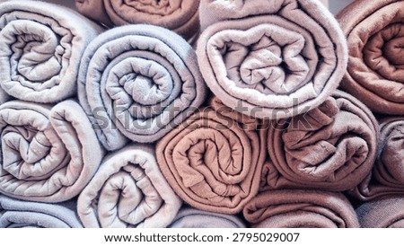 Full frame stack of neatly rolled pastel towels creating a soft and colorful texture background. Cozy fabric arrangement symbolizing cleanliness, comfort, hygiene, relaxation, and home living. Ideal for spa, wellness, bathroom, hospitality, laundry, textile, interior design, and lifestyle concepts.