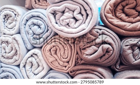 Full frame stack of neatly rolled pastel towels creating a soft and colorful texture background. Cozy fabric arrangement symbolizing cleanliness, comfort, hygiene, relaxation, and home living. Ideal for spa, wellness, bathroom, hospitality, laundry, textile, interior design, and lifestyle concepts.