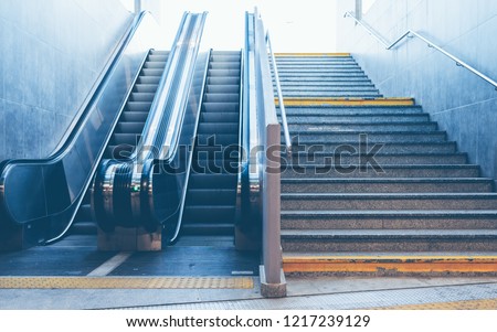 Full frame take of a stone staircase next to a modern escalator