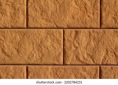 Full Frame Texture Background Of A Modern Textured Brown Color Block Wall In A Running Bond Brickwork Pattern, With Large Concrete Blocks In Sunlight