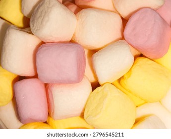 Full frame texture of soft fluffy mini marshmallows in pastel pink, yellow, and white colors. Flat lay