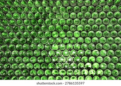 Full frame wall with empty green beer bottles bottoms. Alcohol theme. Endless rows of wine bottles. Green glass bottle wall with sunlight from behind