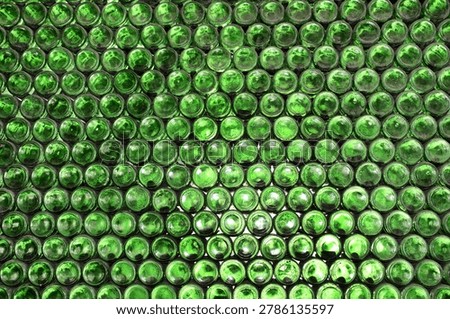 Full frame wall with empty green beer bottles bottoms. Alcohol theme. Endless rows of wine bottles. Green glass bottle wall with sunlight from behind