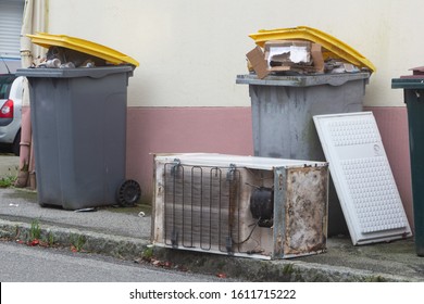 Full garbage bin and left-behind fridge in a street in Brest