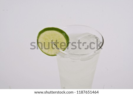Full glass of fresh cool tonic with lime fruits isolated on white background