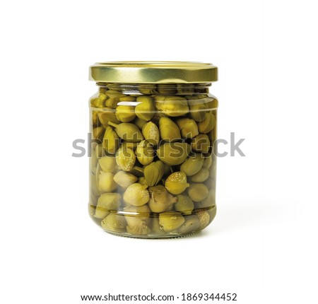 Full glass jar of pickled capers in a brine isolated on white background. Marinated buds of caper bush. Mediterranean cuisine ingredient. Organic spices and seasonings. Front view.