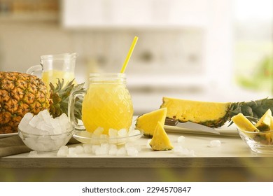 Full glass of pineapple drink with ice on table with crushed ice and fruit and kitchen background. Front view. Horizontal composition. - Powered by Shutterstock