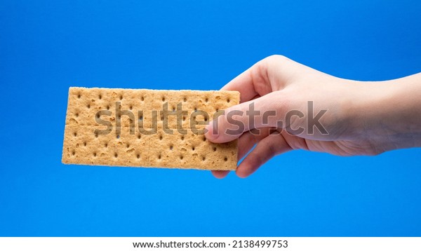 Full Graham\
Cracker In Hand On A Blue\
Background