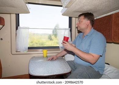 A Full Grown Man In A Train Compartment Is Sitting At A Table With A Mug Of Tea Concept Of Lunch On Journey.