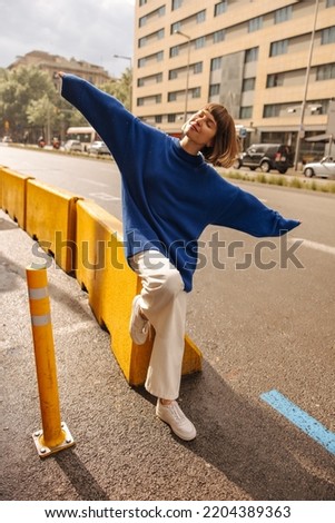 In full growth, funny young caucasian woman, closing eyes, waves arms to sides standing on street. Brown-haired with bob haircut wears casual clothes. Lifestyle concept Stock photo © 