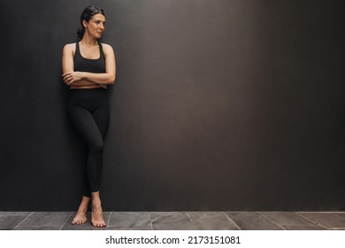 In Full Growth, Pretty Young Caucasian Woman With Good Figure Stands On Black Background With Space For Text. Brunette Wears Sportswear And Leggings. Healthy Lifestyle, Keep Fit Concept.