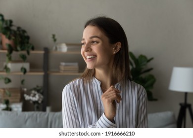 Full of hopes and dreams. Head shot of pretty young woman stand at home look aside with dreamy smile imagine visualize good future. Serene cheerful teenage female loving life enjoy every beautiful day