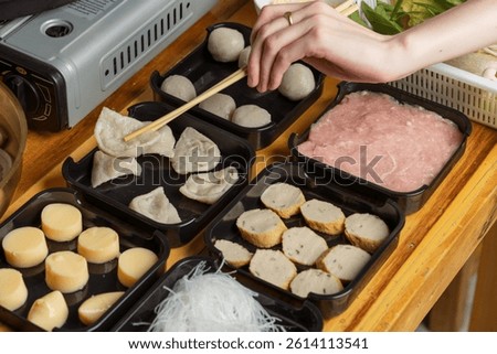 Full hotpot table set with assorted pork, meatballs, and grill pan.