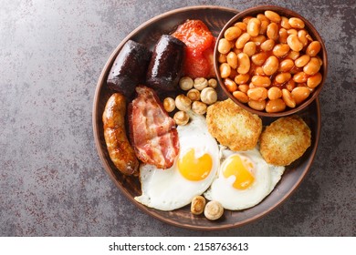 Full Irish Breakfast Black Pudding, Egg, Beans, Sausages, Bacon, Hash Brown, Tomato Closeup In The Plate On The Table. Horizontal Top View From Above
