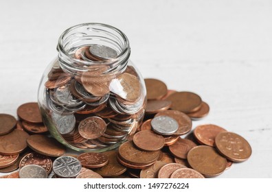 Full jar of coins on a table, with loose change. Money savings concept with copy space. 