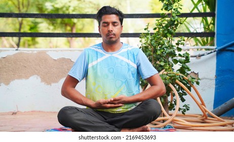 Full Of Joy Young Indian Man Wearing Sports Clothes Blue Shirt And Black Tights In Lotus Position