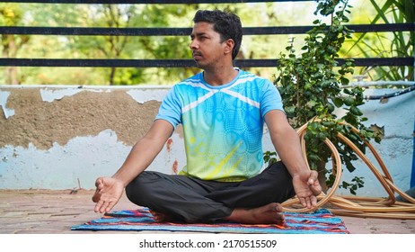 Full Of Joy Young Indian Man Wearing Sports Clothes Blue Shirt And Black Tights In Lotus Position