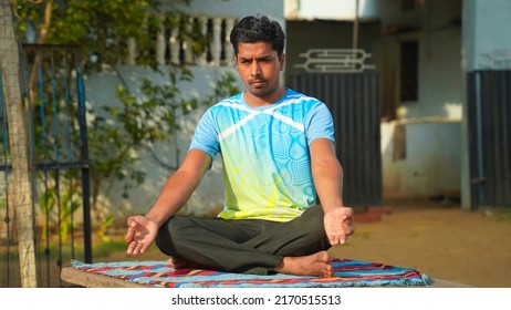 Full Of Joy Young Indian Man Wearing Sports Clothes Blue Shirt And Black Tights In Lotus Position