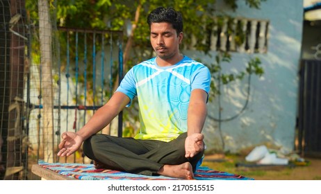 Full Of Joy Young Indian Man Wearing Sports Clothes Blue Shirt And Black Tights In Lotus Position