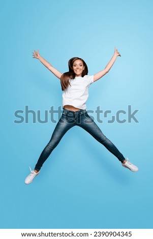 Full lenght portrait of brown-haired gorgeous attractive nice lovely excited smiling young lady wearing jeans and white t-shirt, raising hands up, flying jumping over grey background, isolated