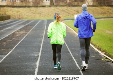 Full Lenght Shot From Behind Of A Young Couple Running Outdoors.