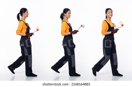 Full length 20s young Asian Woman decoration painter, walking forward left right, wear orange jumpsuit uniform gloves. Smile happy female hold paint roller brush over white background isolated - Powered by Shutterstock