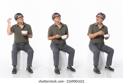 Full Length 50s 60s Asian Chinese Shop Owner Man, Eating Food Chopstick Bowl, Wear Formal Casual Dress Sit On Chair. Old Middle Age Male Sitting And Turn Many Angle Over White Background Isolated