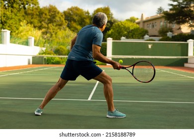 Full length of active biracial senior man holding racket and playing tennis at tennis court. unaltered, sport, competition, retirement, healthy and active lifestyle concept. - Powered by Shutterstock