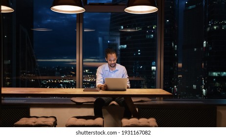 Full Length African American Businessman Working On Laptop In Office At Night Alone, Looking At Screen, Sitting At Desk Near Panoramic Window, Employee Finishing Project At Late Hours, Deadline