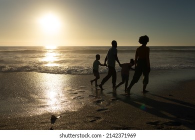 Full Length Of African American Family Holding Hands Walking At Beach During Sunset. Unaltered, Family, Lifestyle, Togetherness, Enjoyment And Holiday Concept.