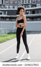 Full Length Of African American Woman In Black Sportswear And White Sneakers Standing On City Stadium