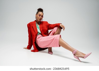 full length of african american woman in bold attire and sunglasses on grey backdrop, dynamic pose - Powered by Shutterstock