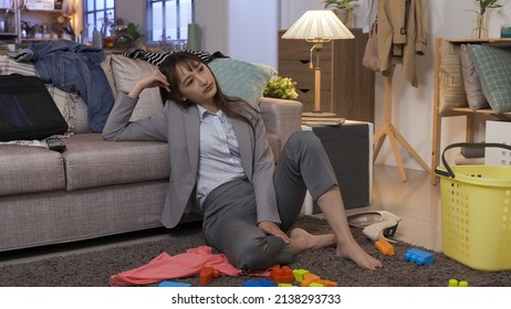 Full Length Asian Lady Wearing Suit Seated In Messy Living Room Propping Head Is Tired Of Doing Housework. Losing Work-life Balance. Real Moments